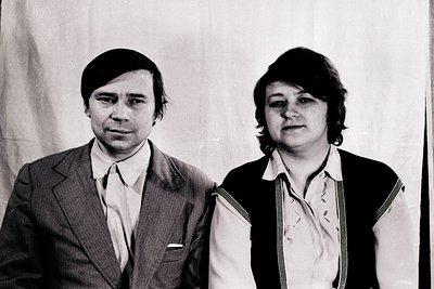 Portrait of two individuals in formal attire, likely from the 1970s. The man wears a suit with a white dress shirt and a butt...