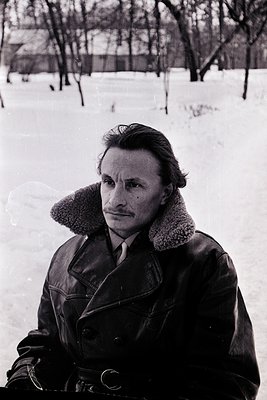 Portrait of a man in a winter coat with fur-lined collar, standing on snow-covered ground. His attire suggests mid-20th centu...