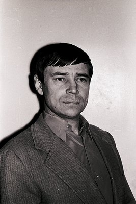 Portrait of a man in a mid-century suit, likely 1960s–1970s. Dark, textured blazer with a subtle shoulder pad, paired with a ...