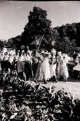 Vintage outdoor procession featuring three participants in straw costumes, likely depicting traditional or folk figures. Crow...