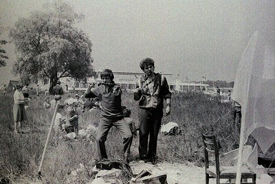 Black-and-white photo of two women in mid-1970s outdoor setting, likely Eastern Europe. One woman holds a camera, the other a...