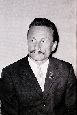 Mid-century formal portrait of a man in a dark suit, white dress shirt, and striped tie. His mustache and short hair suggest ...