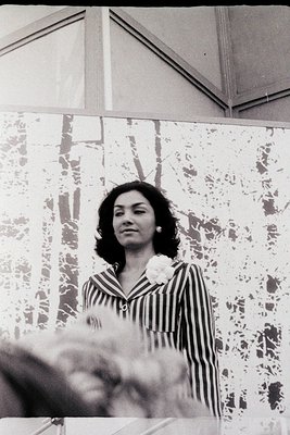 Black-and-white portrait of a woman in a striped blouse with a white flower pinned to her lapel, likely from the 1960s–1970s....