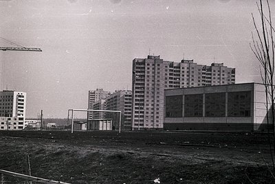 Mid-20th century urban construction site featuring Soviet-era high-rise apartment blocks under development. Prominent concret...