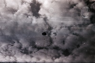 Vintage aerial view of dense cloud formations with faint aircraft silhouettes. Likely mid-20th century military or reconnaiss...