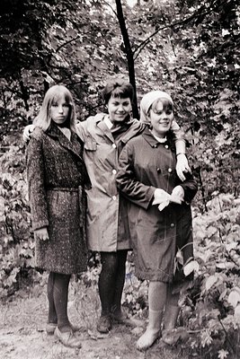Three young women pose outdoors in autumn foliage, 1960s–1970s. Left: long-sleeved patterned coat, knee-length skirt, shoulde...