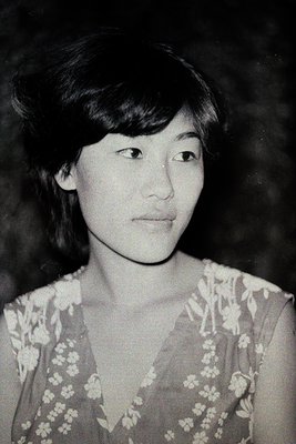 Portrait of a woman in a floral-patterned blouse, likely from the 1960s–1970s. Soft focus and monochrome style suggests vinta...