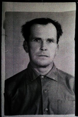 Portrait of a man in a formal, buttoned-up shirt, likely a vintage identification or passport photo. The style suggests mid-2...