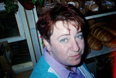 Portrait of an individual with short, layered red hair and a neutral expression, wearing a light blue collared shirt. Backgro...