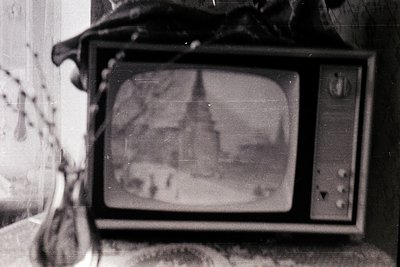 Vintage CRT TV with faded screen displaying indistinct static/ghosting, mounted on a worn wooden stand. Knobs and dials sugge...