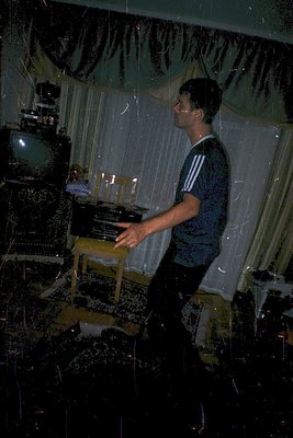 A man in a 1970s-style striped shirt plays a vintage upright piano in a dimly lit room adorned with ornate, beaded curtains. ...