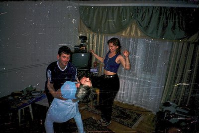 Vintage indoor scene featuring three people dancing in a dimly lit room with a curtained window. The man in a striped shirt a...