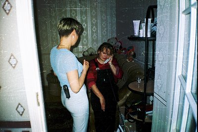 Vintage bathroom interior with patterned tiles and a mirrored cabinet reflecting a woman in red overalls adjusting a child’s ...