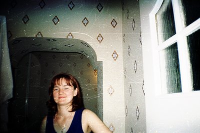 Vintage bathroom interior featuring geometric tile patterns in muted tones. Woman in sleeveless top poses near shower alcove ...