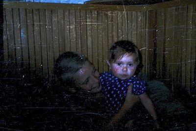 A blurred, intimate moment captured through a frosted glass barrier. An adult and child share a tender connection, their refl...