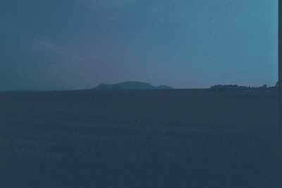Vintage monochrome seascape with minimalist horizon line. Dark, muted tones contrast with distant landmass and faint horizon ...