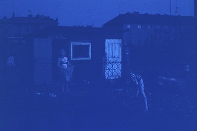 Vintage monochrome photo of two children playing in a courtyard, likely Eastern European . Blurred but visible: one child in ...