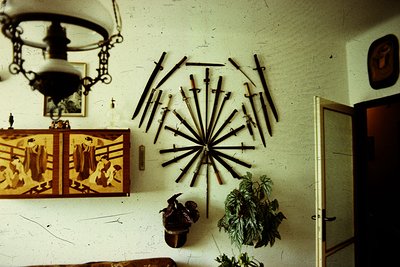 Vintage interior featuring a radial wall display of rustic farming tools arranged like a sunburst. Below, two wooden panels d...