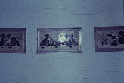 Vintage framed relief sculptures depicting industrial and domestic scenes, mounted on a weathered wall. Left: factory machine...