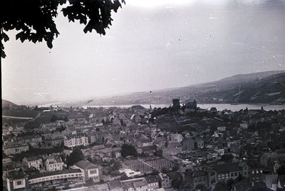 Vintage aerial view of a coastal city with dense, low-rise architecture along a river estuary, likely early-to-mid 20th centu...