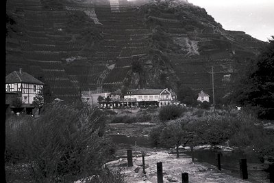 Mid-20th century seaside resort with tiered cliffs and wooden buildings, likely . Architectural style blends functionalist de...