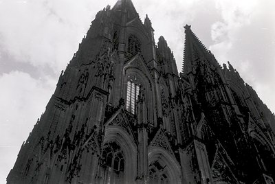 Gothic cathedral façade featuring pointed arches, intricate tracery, and vertical spires. Symmetrical design with rose window...