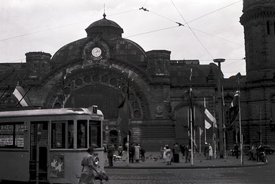 Historic tram station with grand archway and clock, likely Sofia Central Railway Station (). Soviet-era flags and Cyrillic si...