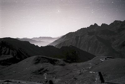 Vintage black-and-white alpine landscape with jagged peaks and misty valleys, likely captured via early aerial or high-altitu...