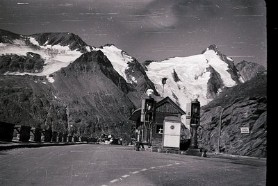 Vintage alpine station with vintage cable car terminal and snow-capped peaks in background. Mid-20th century mountain resort ...
