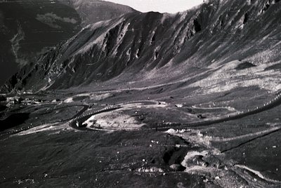 Aerial black-and-white photo of a volcanic crater in a rugged mountainous landscape, likely captured mid-20th century. The cr...