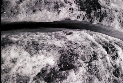 Close-up of frothy, turbulent ocean waves crashing onto a rocky shore. High-contrast black-and-white composition highlights t...