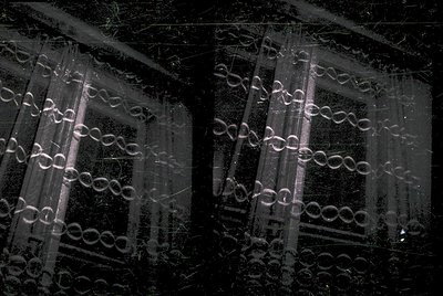 Double-exposure nighttime shot of Venetian-style window blinds with intricate diamond patterns, backlit by streetlights. Urba...