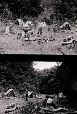 Mid-20th century outdoor camping scene with military-style tents and log structures. Group of men in utilitarian clothing (e....