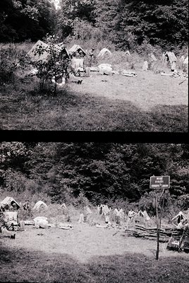 Historic rural settlement with stone huts and primitive structures in a forested area. Signpost reads "Village of **Bulbucata...