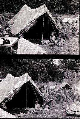 Mid-20th century military or scout camp in forested terrain. Tent structures with canvas and wooden poles, likely 1950s–1960s...