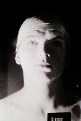 Black-and-white portrait of a young man in a studio setting, likely 1950s–1960s. Clean-shaven with short hair, wearing a head...