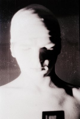 Vintage sepia-toned portrait of a young child with blurred facial details, likely mid-20th century. The child wears a simple,...