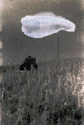 Vintage aerial photo of a lone military jeep traversing a snow-covered landscape, likely post-WWII. The vehicle appears to be...