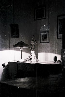 Mid-century modern bedroom interior with vintage desk setup. Wooden desk features a sculptural lamp, framed art, and a manneq...