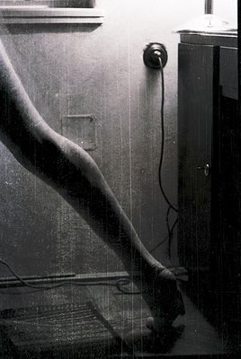 Vintage black-and-white close-up of a wall-mounted telephone with coiled cord and wall socket. Mid-century design with visibl...