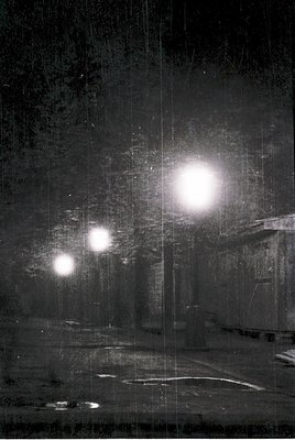 Vintage black-and-white photo of a dimly lit industrial tunnel with three bright light sources illuminating the dark space. V...