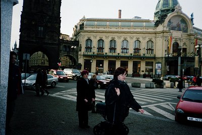 Historic urban scene featuring a grand Beaux-Arts-style building with ornate facades and domed roof, likely a railway station...