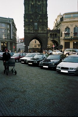 Historic cobblestone street in Budapest with a grand Gothic Revival archway and tower, likely the **Fisherman’s Bastion** ent...
