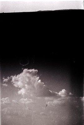 Vintage aerial shot of dramatic cumulus clouds over flat terrain, likely taken from a small aircraft. The low-angle perspecti...
