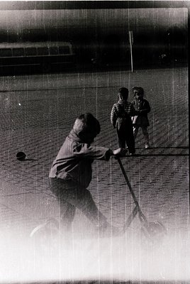 Vintage black-and-white photo of three children playing with a net and ball in an indoor sports facility, likely a gymnasium....