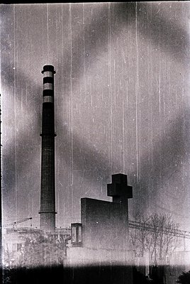 Industrial smokestack complex with dual tall chimneys and adjacent rectangular buildings, likely a power plant or factory. He...