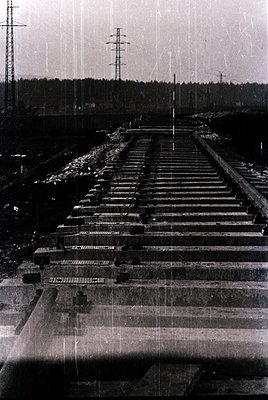 Vintage black-and-white photograph of a long, straight railway track with multiple freight cars, likely coal or ore, arranged...