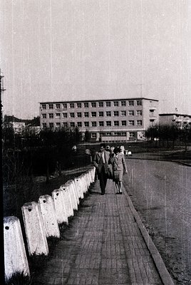 Mid-century concrete bridge with concrete barriers leads to a multi-story institutional building, likely a hospital or dormit...