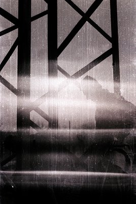 Vintage black-and-white shot of a woman silhouetted against geometric window frames, likely from a Soviet-era building. Sunli...