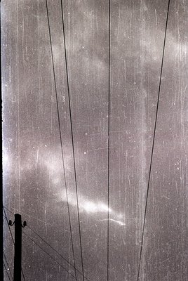 Close-up of weathered concrete wall with diagonal cracks and embedded metal rebar, showing signs of aging and structural wear...